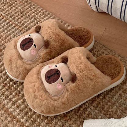 Light brown fuzzy plush slippers showcasing a capybara face with cream patch and dark snout, cozy indoor footwear with PVC sole