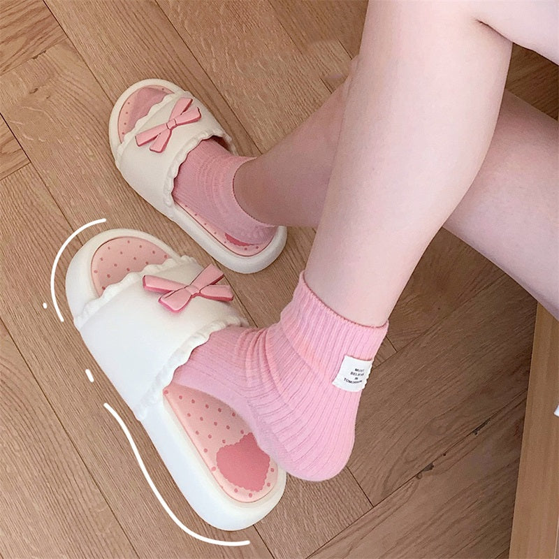White EVA slip-on slippers featuring a 3D pink bow with scalloped trim and a pink polka dot footbed, lightweight indoor footwear