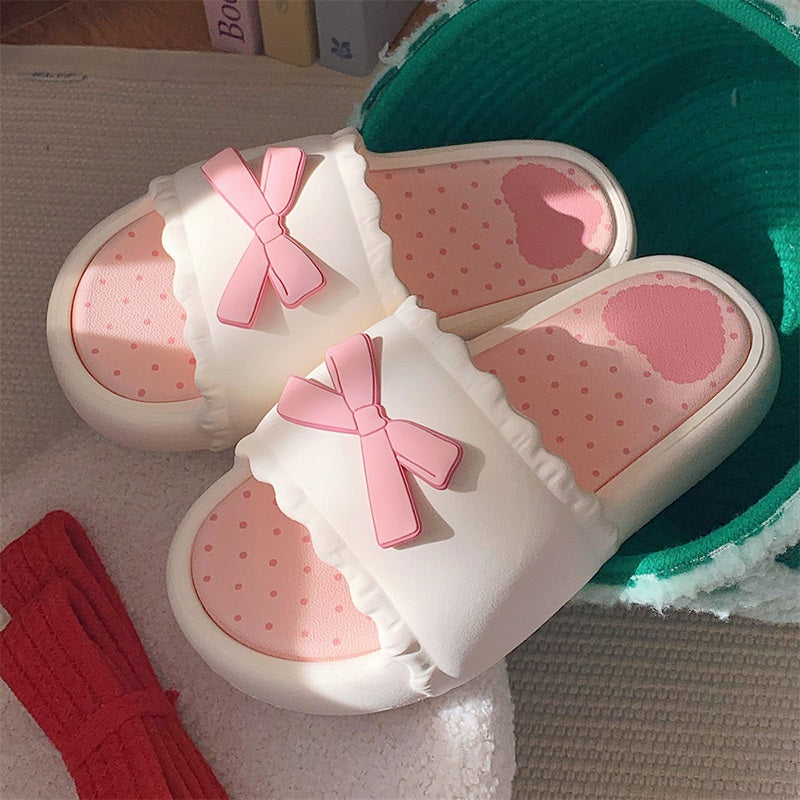 White EVA slip-on slippers featuring a 3D pink bow with scalloped trim and a pink polka dot footbed, lightweight indoor footwear