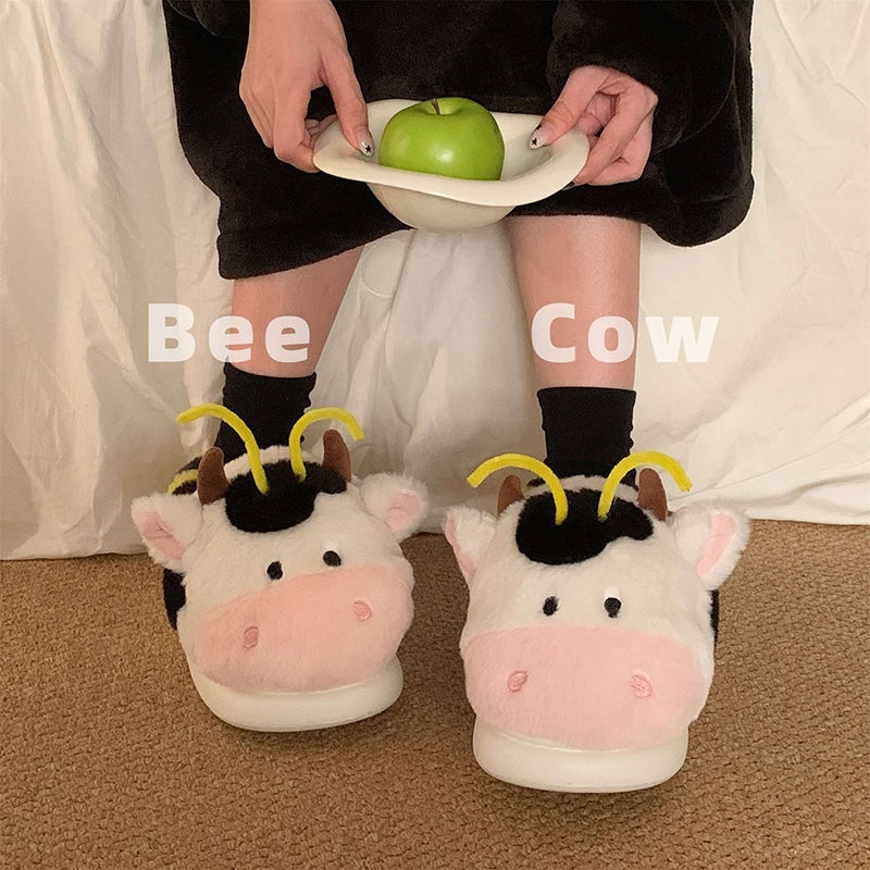 Cute pink cow and bee plush slippers with black patches, yellow stripes, and yellow antennae, closed-back fuzzy indoor shoes with EVA sole