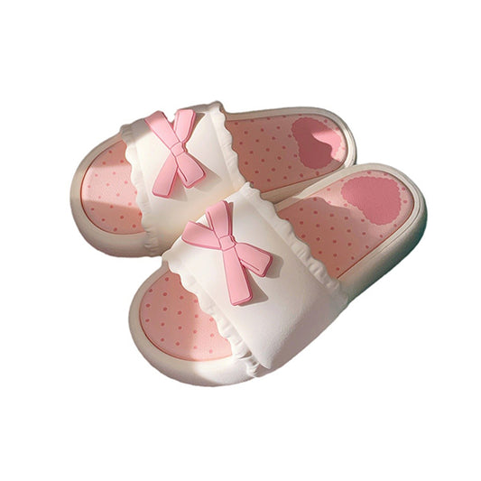 White EVA slip-on slippers featuring a 3D pink bow with scalloped trim and a pink polka dot footbed, lightweight indoor footwear