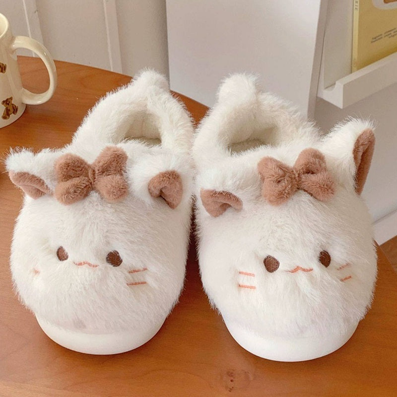 Beige closed-back plush slippers featuring a bow cat design with line eyes and a tiny tail, warm indoor footwear with EVA sole